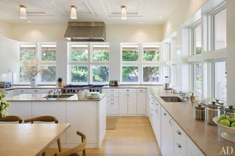 Белая кухня с бежевым оттенком и большими окнами