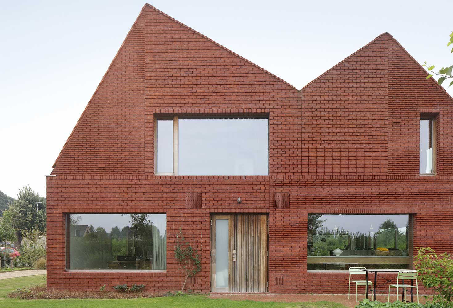 Facade of a two-story brick house with a roof stylized as brickwork