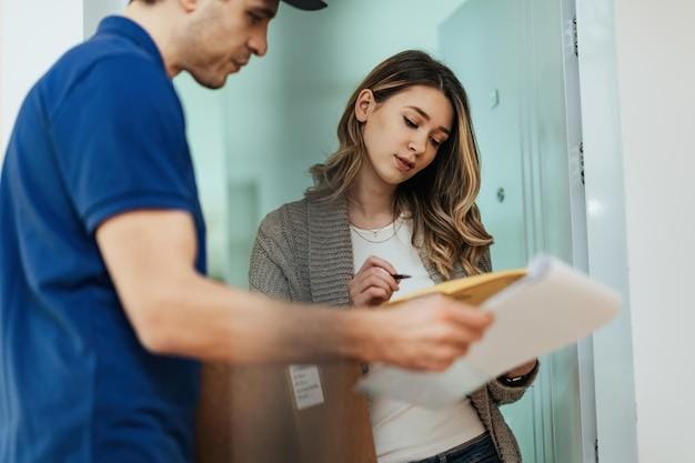 Free photo low angle view of woman signing to delivery man while standing on a doorway