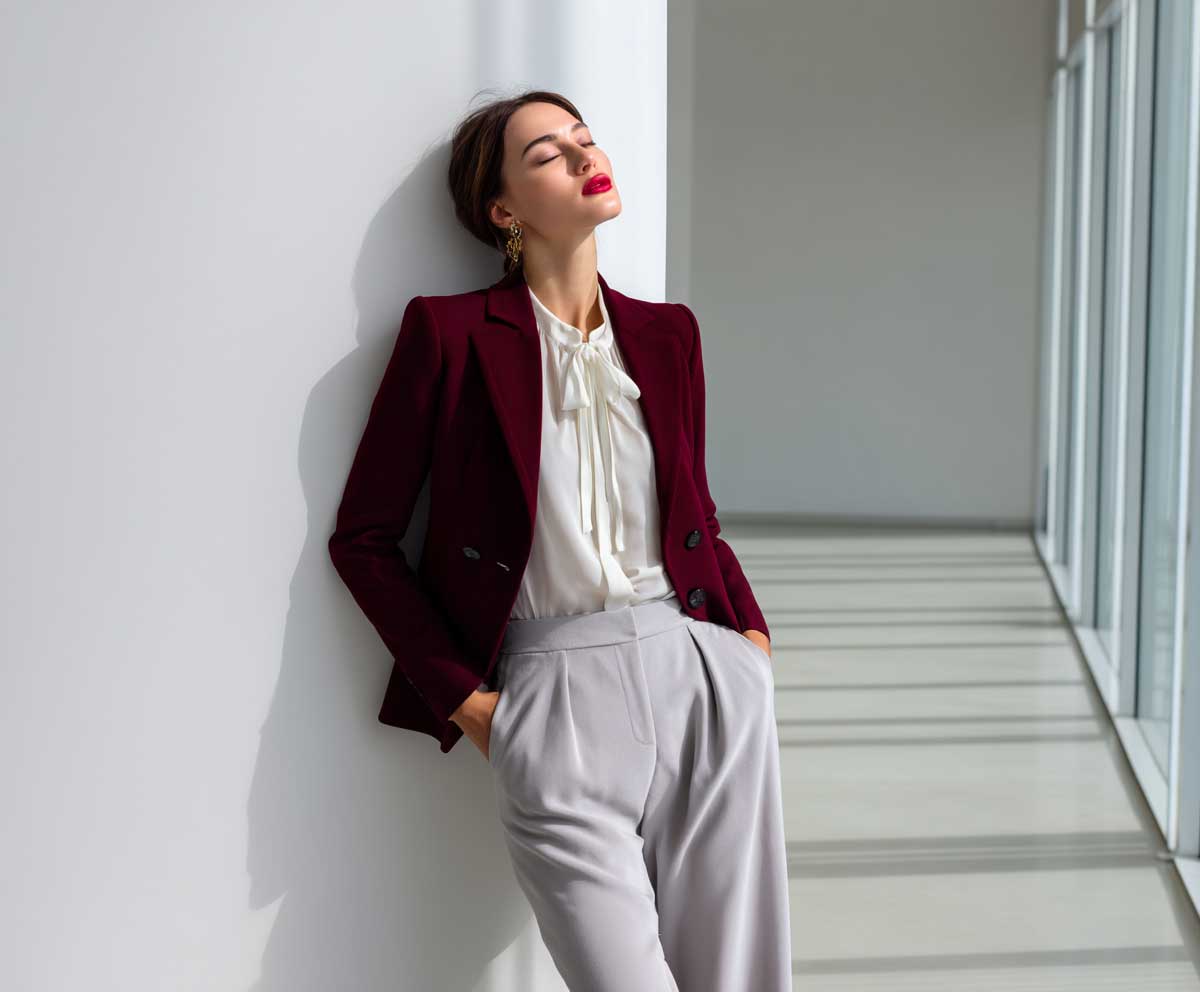 confident female model wearing burgundy tailored blazer, white blouse, light gray wide leg pants, professional office environment, minimal accessories, soft lighting, modern business casual fashion