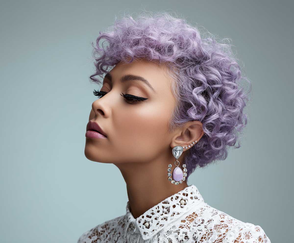 close-up fashion photo of a woman with a lavender violet curly pixie cut, defined side part, sculpted curls, soft background, dreamy lighting, studio setting with pastel styling