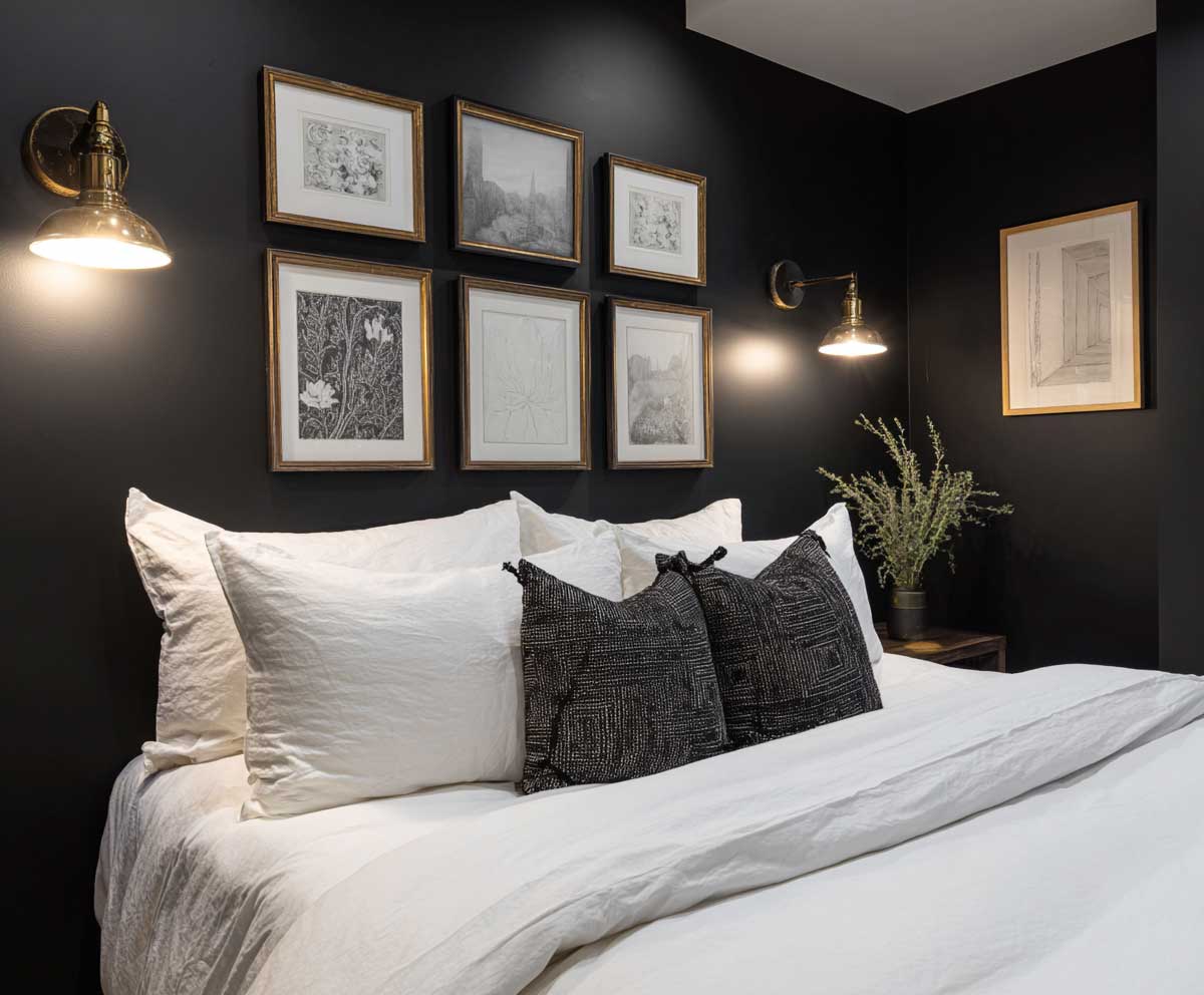 guest bedroom with black feature wall, crisp white bedding, black and white framed art, modern wall sconces, high contrast monochrome color scheme, moody lighting, elegant minimalist design