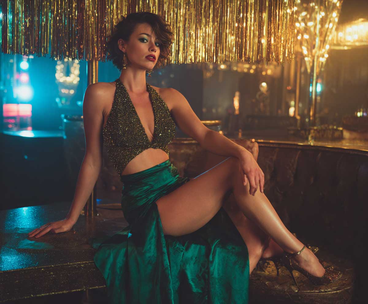 glamorous photo of a woman in a glittery halter neck top and an emerald green skirt with a high front slit, evening lighting, nightclub interior, high heels, bold eye makeup, shimmering effect
