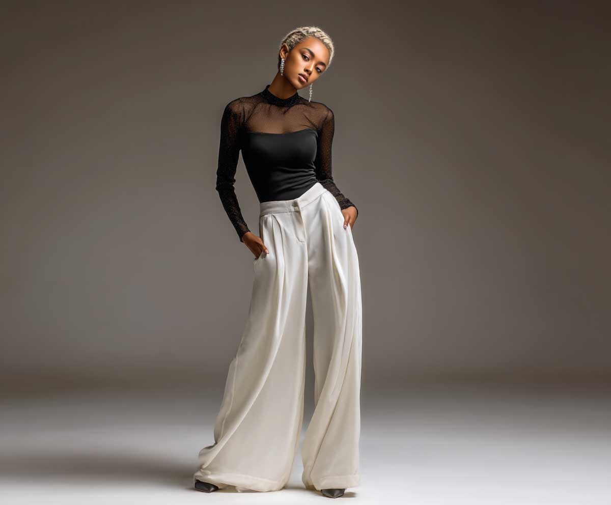 fashion model in black semi-sheer long sleeve bodysuit and ivory wide leg trousers, soft studio lighting, neutral background, elegant standing pose, modern styling, full length image