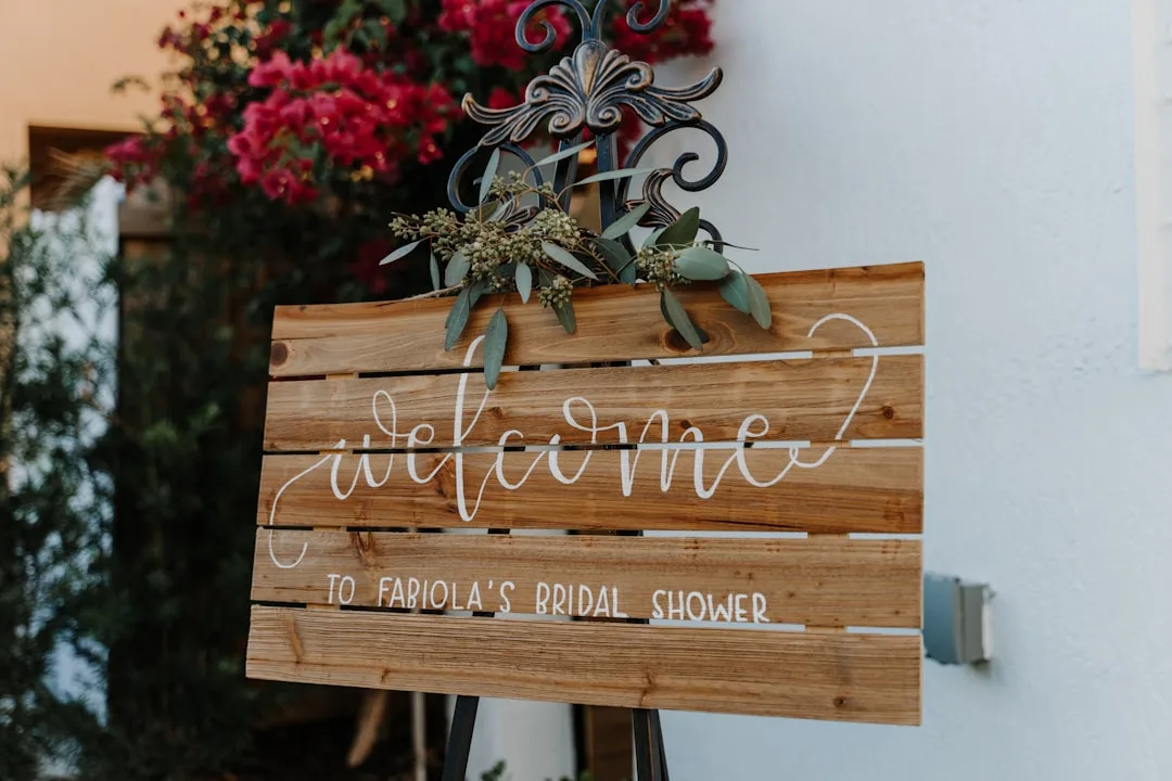 Layered wooden wedding welcome display with greenery and string lights