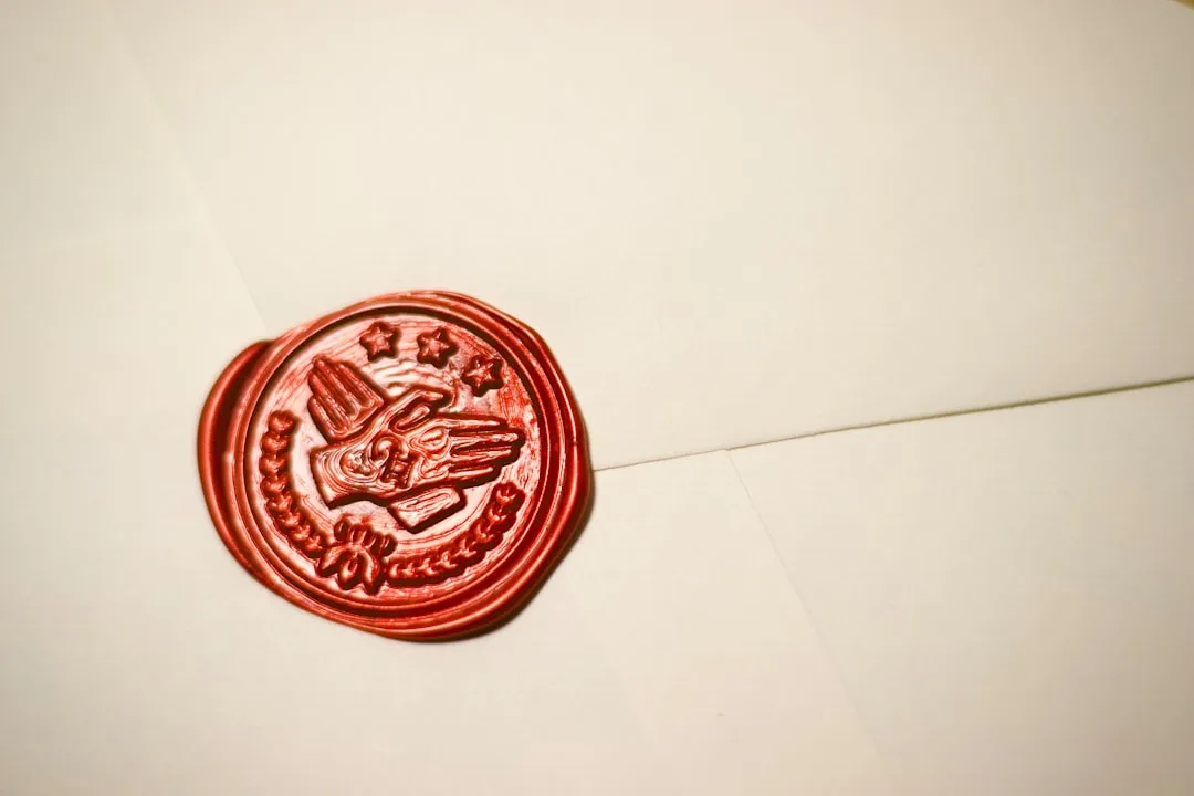 Wax seal stamp being applied to envelope flap in deep emerald