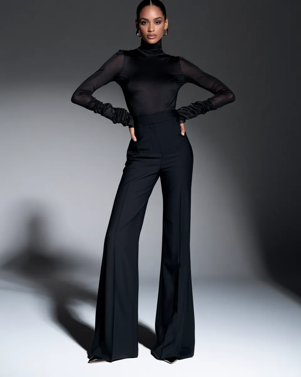 Fashion magazine studio shot of a woman in a sleek fashionable black look, standing full body, editorial lighting, modern and striking composition.