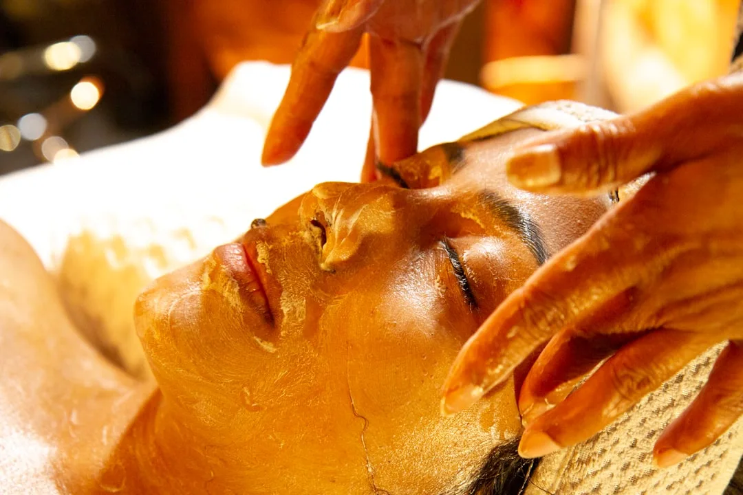 Close-up of hands demonstrating facial oil layering technique on hydrated skin