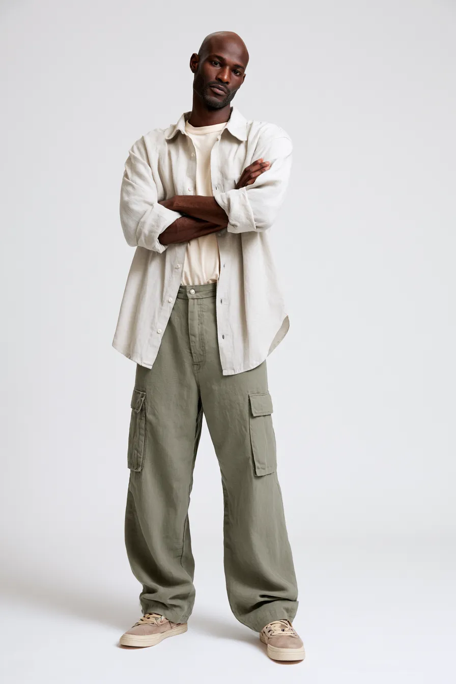 Studio fashion shot of a man wearing a casual menswear outfit with cargo trousers and oversized shirt
