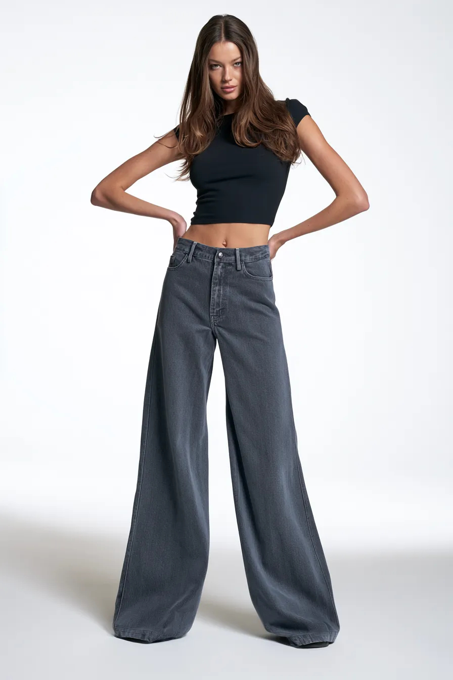 Full-body studio shot of a model in a chic casual look with wide-leg jeans and minimalist accessories