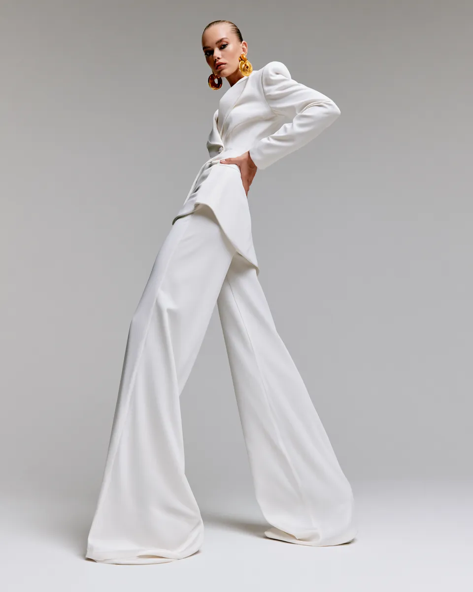 Fashion editorial model in white clothing standing pose, sleek white wardrobe styling with accessories