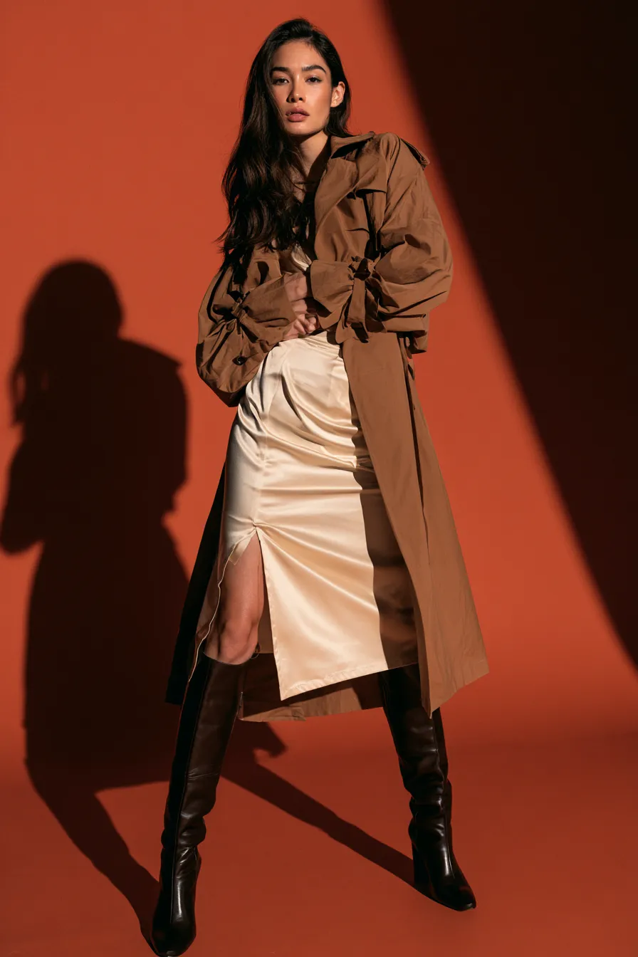Falda midi con trinchera cropped satén y botines largos invierno