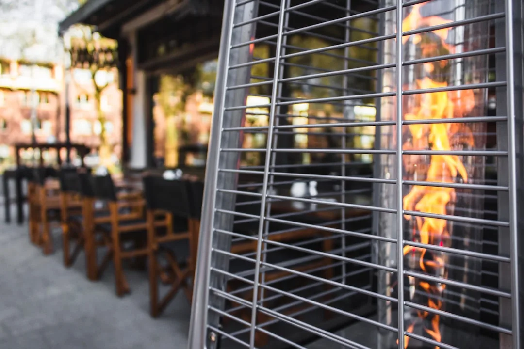 Sleek black infrared patio heater mounted on modern pergola above seating zone