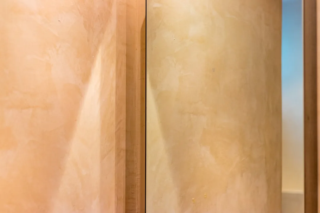 Lime plaster accent wall in bedroom showing warm, matte surface with organic variation