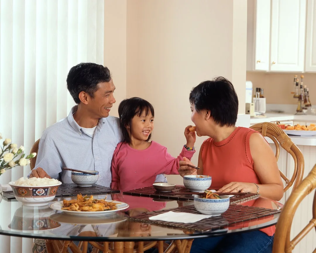 Multi-generational family sharing meal at wooden table with natural lighting and conversation