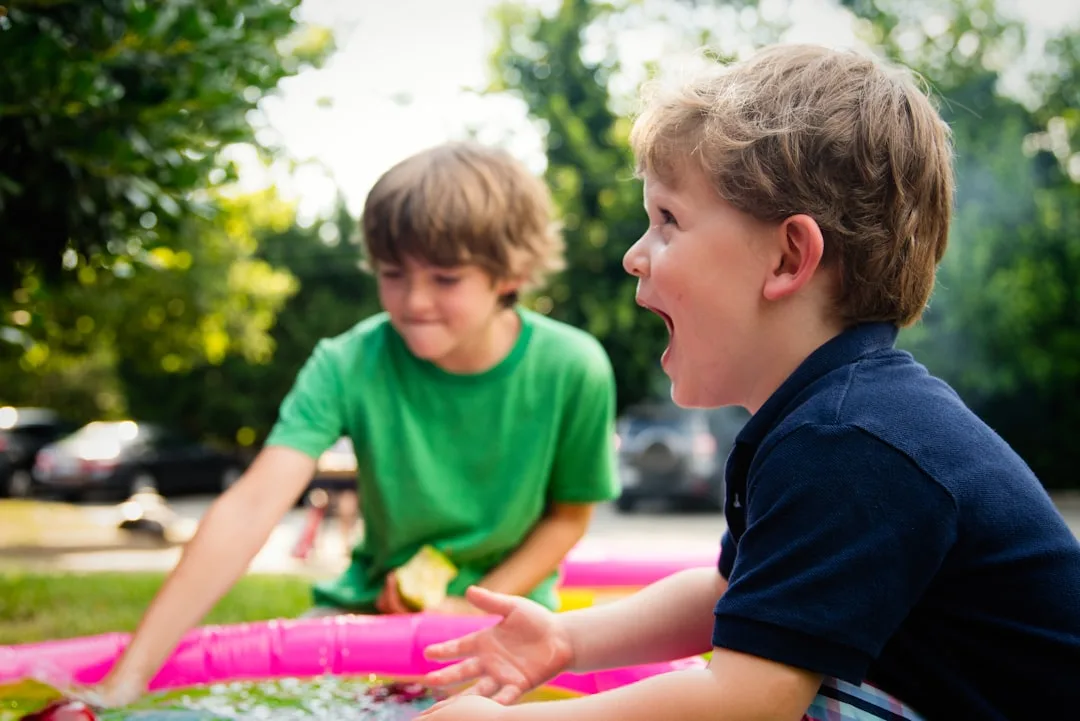 Parent sitting with one child while sibling plays independently nearby