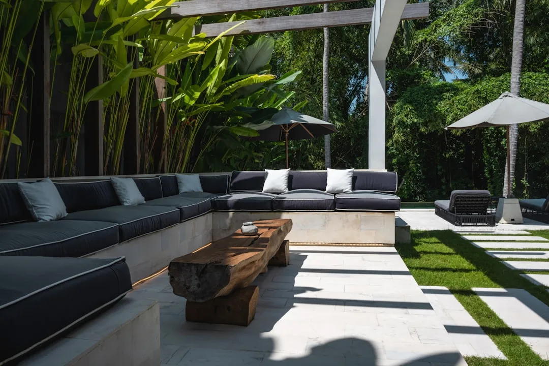 Built-in concrete outdoor bench seating along patio edge with cushions and throw pillows