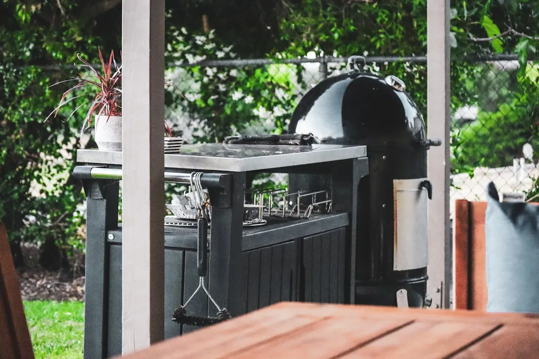 Grey stone outdoor kitchen island with built-in grill and counter seating in patio
