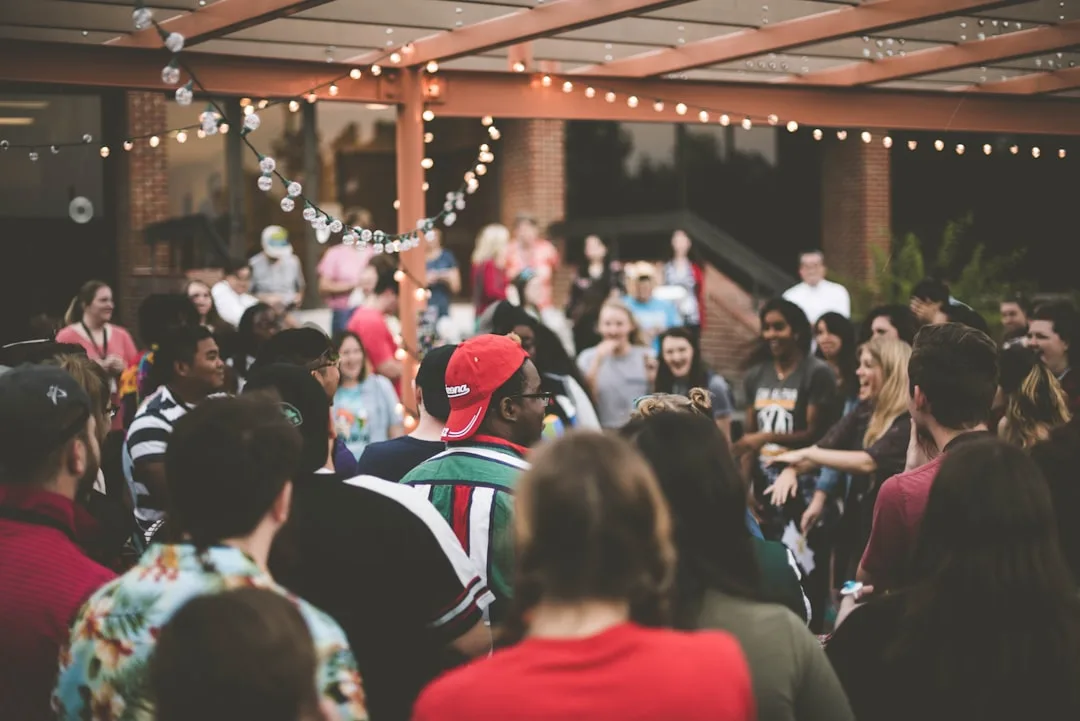 Outdoor welcome back party event with autumn decor and guests mingling