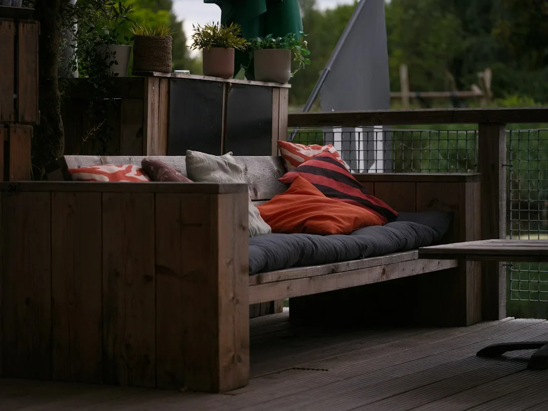 Tiered patio with shade sail and thermal mass wall creating microclimate zones