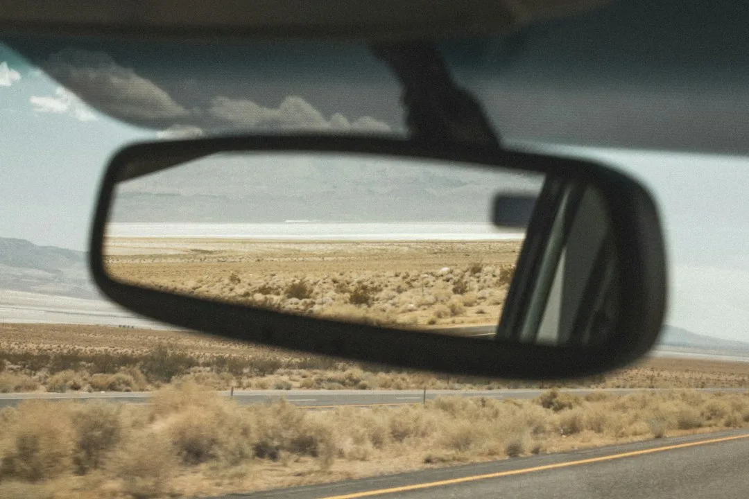 Driver checking blind spot mirror before changing lanes safely