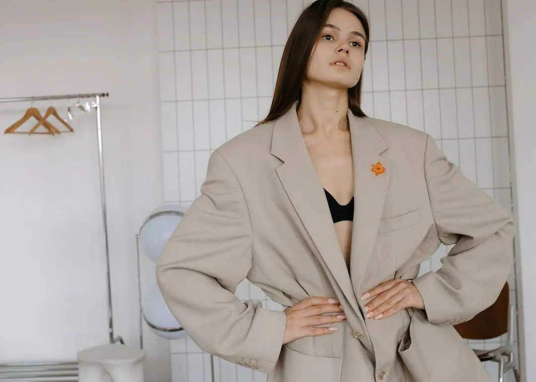 Woman wearing oversized camel blazer with white crop top and tailored trousers