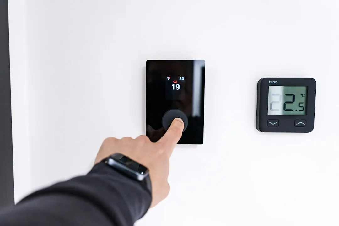Smart thermostat installation on white wall with smartphone app display
