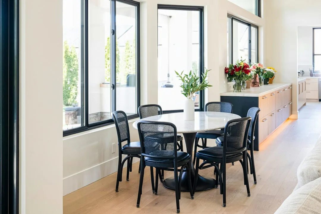 Set of cane dining chairs beside a lime-washed plaster wall and a pendant light