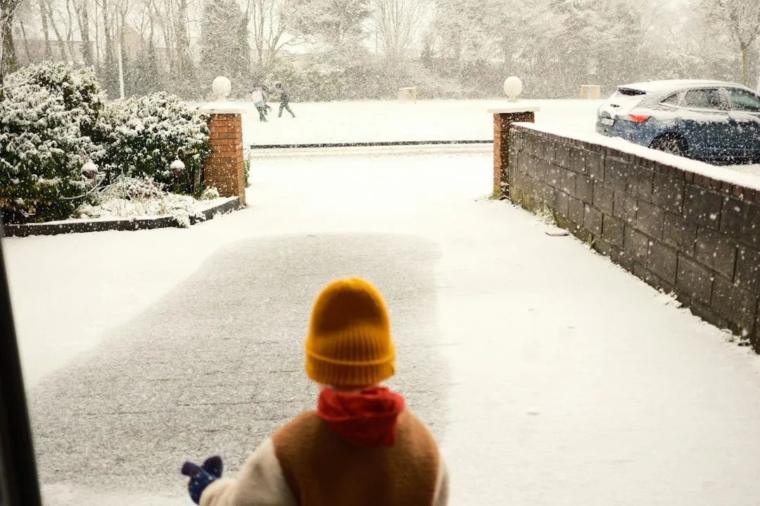 Winter tires with deep tread gripping packed snow on a driveway