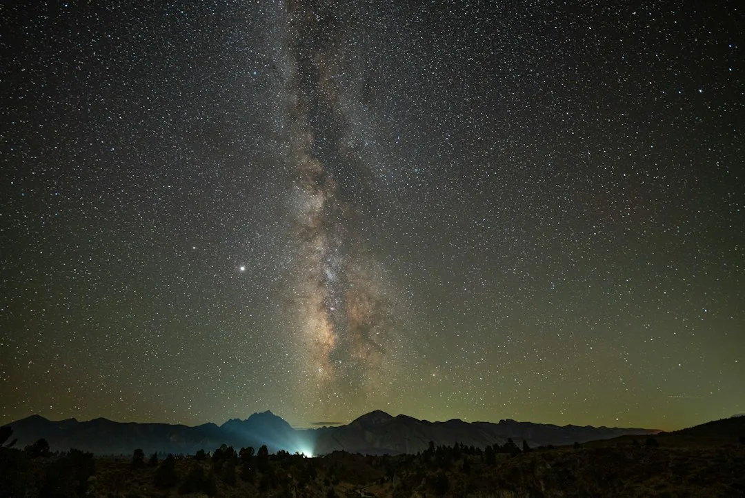 Telescope set up on a tripod beside a desert campsite under a dark sky