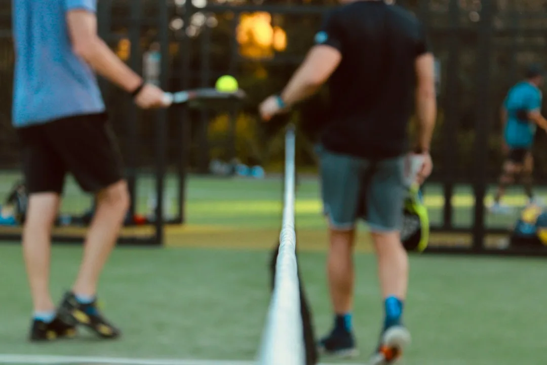 Adults practicing pickleball training drills on an outdoor court with paddles
